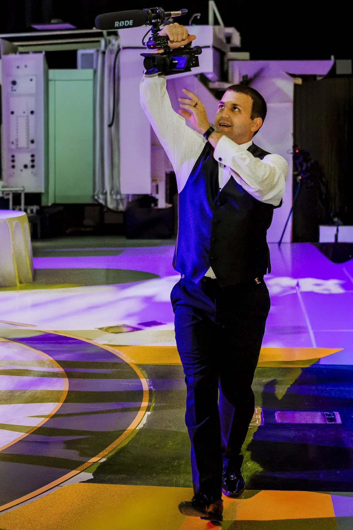 Evan holding a video camera overhead at a wedding reception